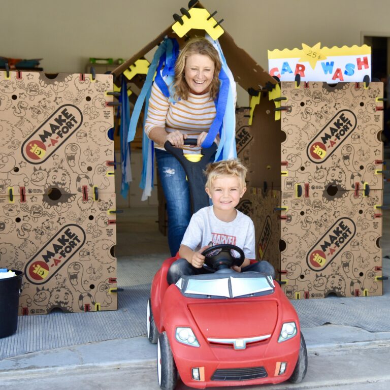 Abuela y nieto jugando dentro de un lavadero de coches de cartón